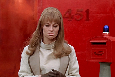 Julie Christie olha para baixo, sob fundo vermelho